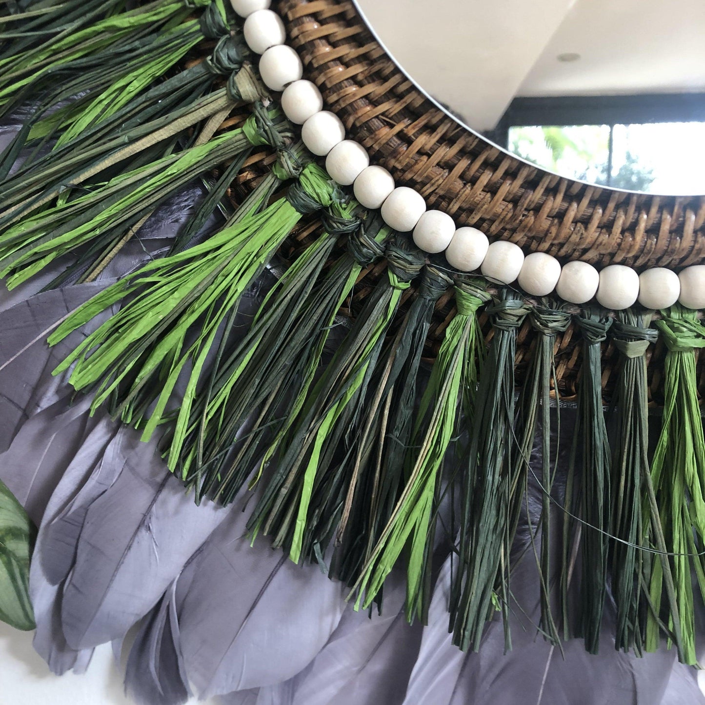 Woody-scented mirror, green raffia and feathers